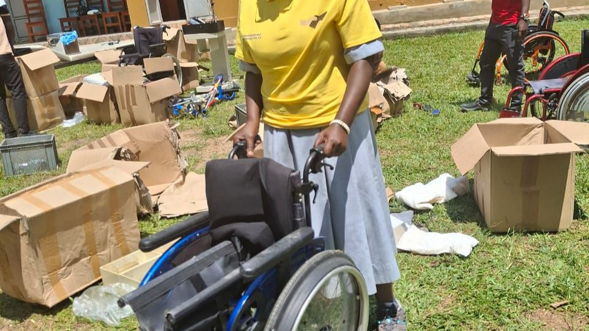 Eine junge Frau in Uganda hält den Rollstuhl, den sie aus einem Hilfstransport der Ugandahilfe Verl erhalten hat.
